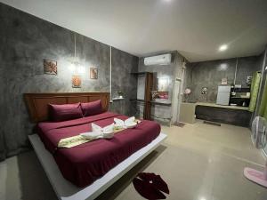 a bedroom with a large red bed with two white towels at Lanta natural hut garden in Ko Lanta