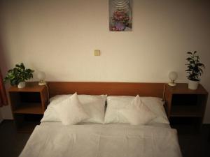 uma cama com lençóis brancos e almofadas num quarto em Hotel Amos em Fulnek