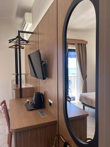 a mirror in a room with a desk and a television at Hotel Al Faro in Licata