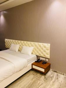 a bedroom with a white bed and a wooden table at Barkah inn in Kannur