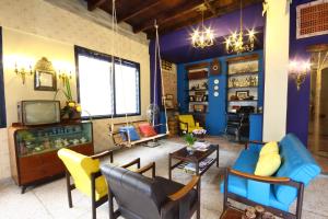 a living room with yellow and blue chairs and a tv at Baan Nai Nakhon in Songkhla