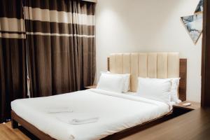 a bedroom with a bed with white sheets and pillows at Capetown Shaadows in Igatpuri