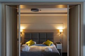 Un dormitorio con una cama grande con almohadas amarillas. en Amrita Hotel, en Liepāja