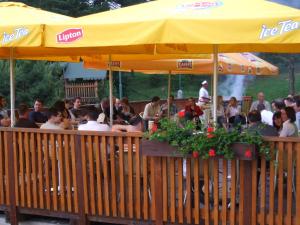 un grupo de personas sentadas en un restaurante bajo un paraguas amarillo en Park Hotel Čingov en Smižany