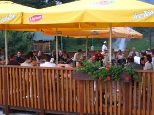 a group of people sitting at a restaurant under a yellow umbrella at Park Hotel Čingov in Smižany