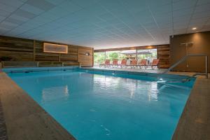 a large swimming pool with blue water in a building at Hotel Alpensonne in Bad Wiessee