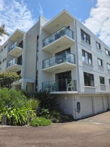 a white apartment building with a parking lot at Pleasant View Apartment - Ocean View in Caloundra