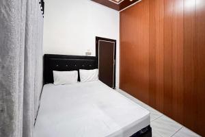 a small bedroom with a bed with a wooden door at Kostel 99 Pangkal Pinang RedPartner in Pangkal Pinang
