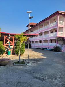 a pink building with a palm tree in front of it at ลพบุรีทาวน์ Lopburi Town in Lop Buri