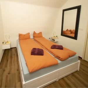 a bedroom with two beds with orange sheets and a mirror at Studio De Gravin in Gouda