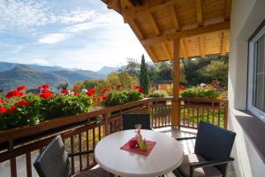 a balcony with a table and chairs and flowers at St. Josefhof in Caldaro