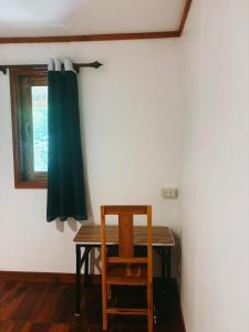 a dining room table with a chair and a window at Thavisok Guest House in Nongkhiaw