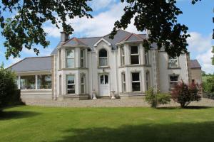 ein großes Haus mit einem Rasenplatz davor in der Unterkunft Ballyhargan Farm House in Dungiven