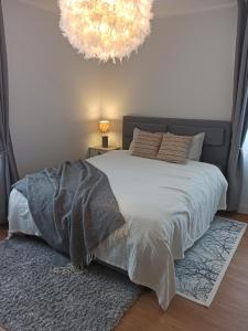 a bedroom with a bed with a blanket and a chandelier at Relax Inn Otepää Apartment in Otepää
