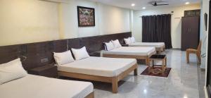 a room with three beds and a couch at SGS Residency in Tirupati