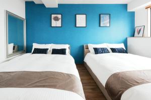 two beds in a room with a blue wall at Prosper 47th bldg in Nagoya