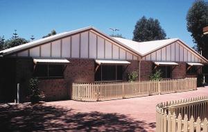 a large brick building with a fence in front of it at Esperance Holiday Apartment in Esperance