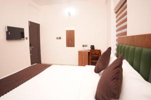 a bedroom with a white bed and a television at Pearl Suites in Cochin