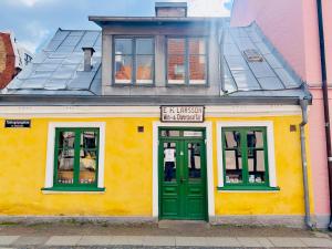 ein gelb-grünes Gebäude mit einer grünen Tür in der Unterkunft Studio 32 in Lund