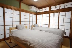 zwei Einzelbetten in einem Zimmer mit Fenstern in der Unterkunft ゲストハウス ブランク Guest House BLANC in Hiroshima