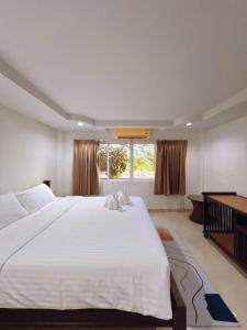 a large white bed in a room with a window at Hello Jomtien in Jomtien Beach