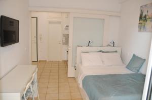 a white bedroom with a bed and a television at Sunset by the sea 2 in Loutraki