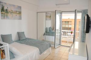 a white bedroom with a bed and a balcony at Sunset by the sea 2 in Loutraki