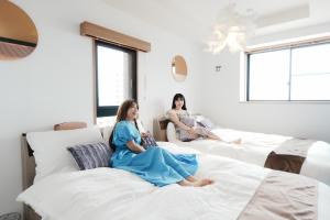 two women sitting on beds in a room at Prosper 47th bldg in Nagoya