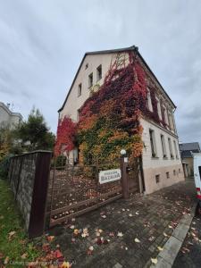a building covered in ivy next to a fence at Penzion Bazalka in Jablonec nad Nisou