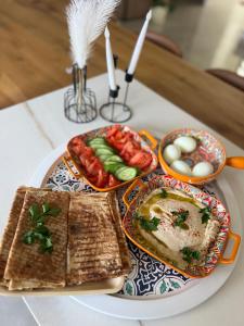 a table with a plate of food with eggs and bread at Golan Zimmer - צימר הגולן in Mas'ada