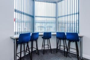 a bar with blue stools in front of a window at Spacious 6-Bedroom Central Blackpool in Blackpool