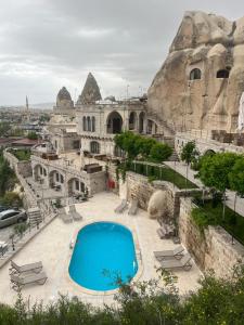 a large building with a blue pool in front of it at Cappadocia Secret Hill Cave Suites in Göreme