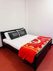 a bed with a red blanket on top of it at D Villa Nuwara Eliya in Sita Eliya