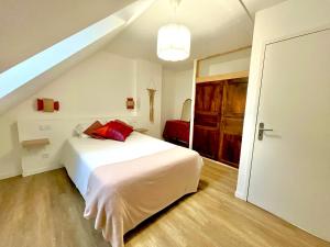 a bedroom with a white bed with red pillows at Le Mandragot - Séjour en Aspe in Bedous