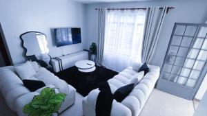 a white living room with a couch and a table at EBM Homes in Nairobi