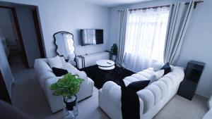 a living room with two white couches and a table at EBM Homes in Nairobi +1 photo