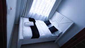 a bed with black and white pillows and a window at EBM Homes in Nairobi