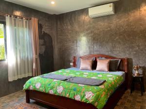 a bedroom with a bed with a green blanket at Baan Mada Lanta villa in Ko Lanta