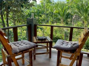 a porch with two chairs and a table and trees at Baan Mada Lanta villa in Ko Lanta
