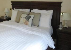 a large bed with white sheets and pillows at EBENEZER Cottage in Discovery Bay
