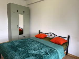 a bedroom with a bed with two orange pillows at Likas cozy corner in Tbilisi City