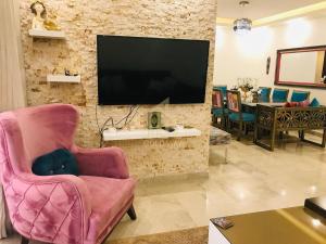 a living room with a pink chair and a flat screen tv at Chic 2-Bedroom - Fully Furnished in Amman
