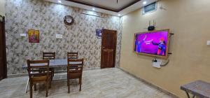 a dining room with a table and a tv on a wall at Lavanya Regency Floor Kanchipuram in Kanchipuram