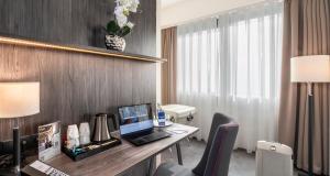 ein Hotelzimmer mit einem Schreibtisch, auf dem ein Laptop steht in der Unterkunft PLAZA INN Mannheim in Mannheim