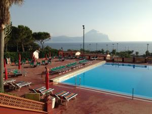 une grande piscine avec des chaises longues et l'océan dans l'établissement Happy Camp Mobile Homes in El-Bahira Camping Village, à San Vito Lo Capo