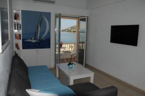 a living room with a couch and a table and a tv at Sunset by the sea 1 in Loutraki