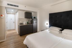 a bedroom with a large white bed and a kitchen at Netanya SeaView ApartHotel in Netanya +142 photos