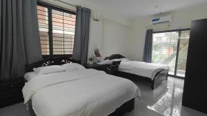 a bedroom with two beds and a window at HUAMENG Hotel in Dhaka