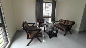 a living room with two chairs and a glass table at HUAMENG Hotel in Dhaka