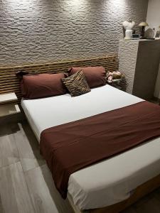 a large bed with brown and white sheets and pillows at The Incantation Guest House in Montesilvano